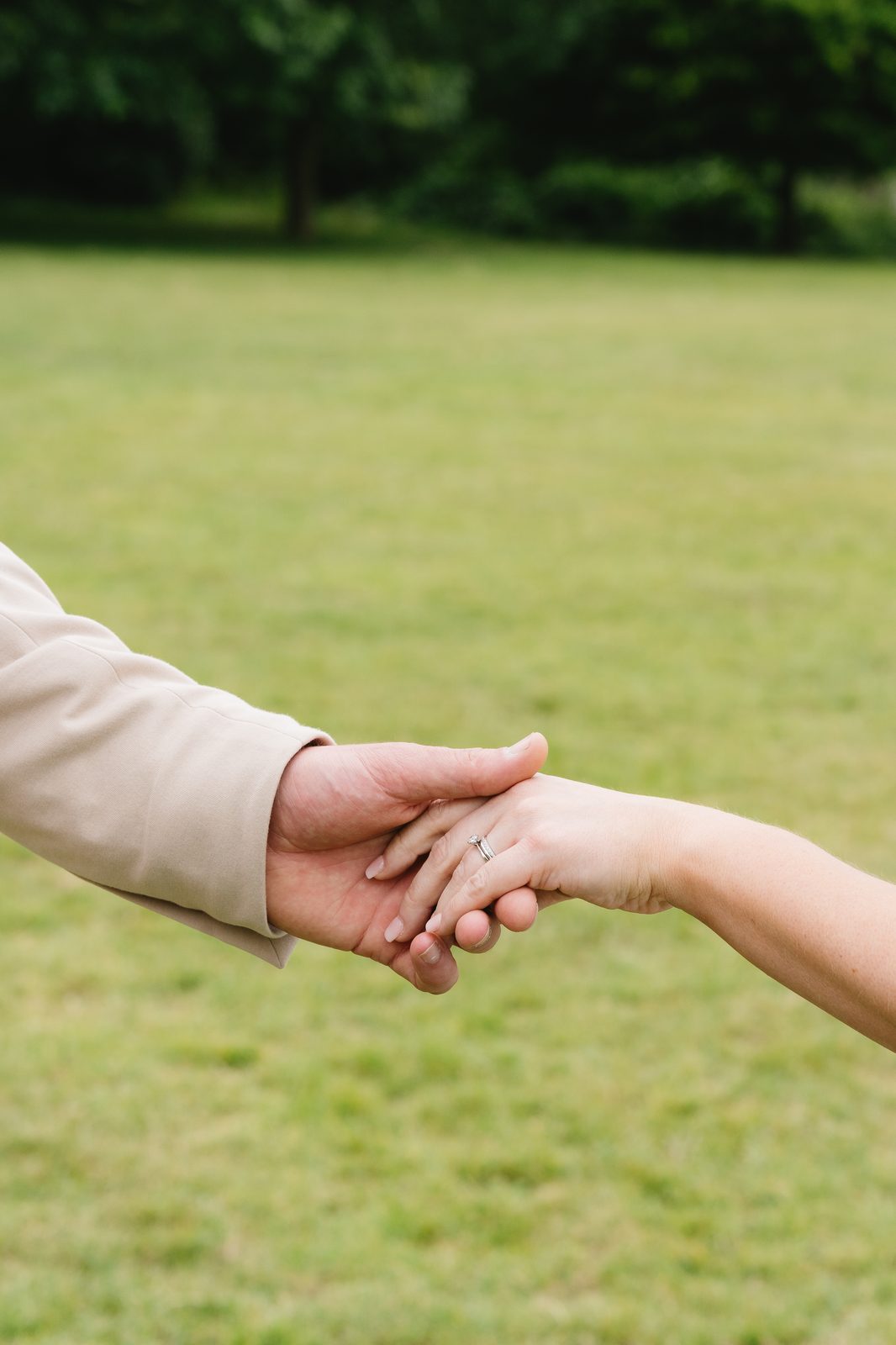 Couple holding hands, wedding ring detail
